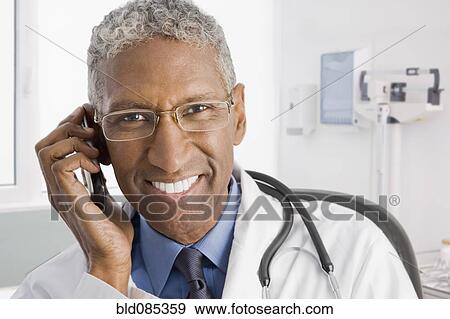 Smiling mixed race doctor talking on cell phone View Large Photo Image Stock Photo - Smiling mixed race doctor talking on cell phone. Fotosearch