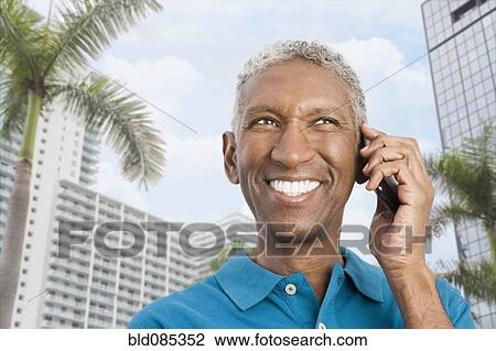 Stock Image - Smiling mixed race man talking on cell phone. Fotosearch