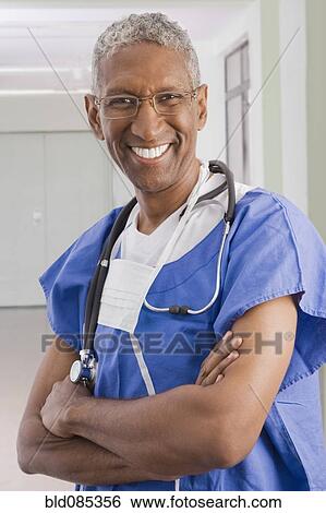 Stock Photograph - Smiling mixed race surgeon with arms crossed. Fotosearch