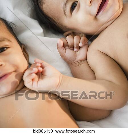Stock Image - Smiling mixed race twins laying together. Fotosearch