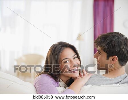 Stock Photo - Smiling sitting together on sofa. Fotosearch
