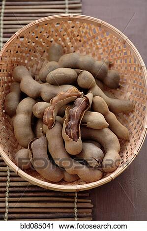 Stock Image - Tamarind pods in wicker basket. Fotosearch
