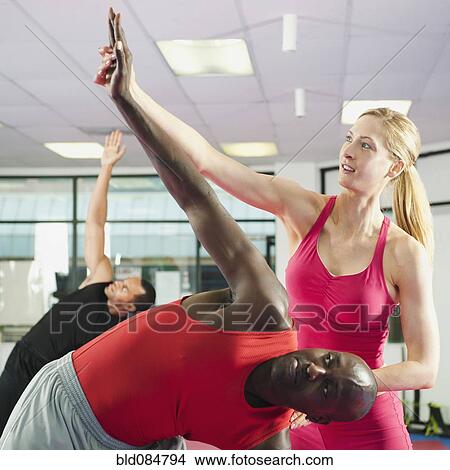 Picture - Teacher helping people in exercise class. Fotosearch