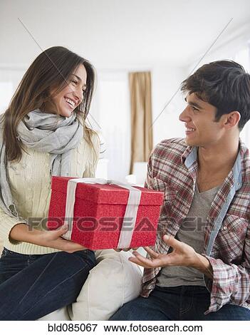 Stock Photo - Woman handing husband Christmas gift. Fotosearch