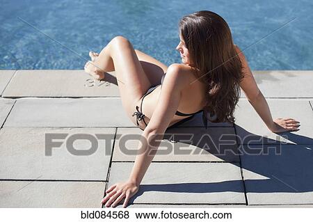 Stock Photo - Woman sunbathing near swimming pool. Fotosearch