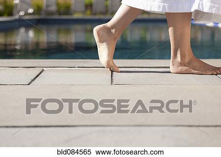 Stock Photography - Woman walking near swimming pool. Fotosearch