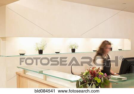 Stock Image - Woman working at spa resort desk. Fotosearch