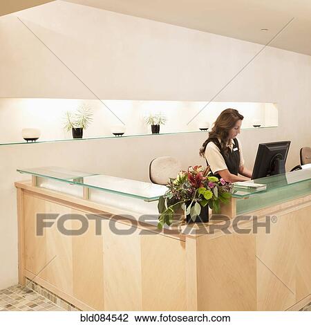Stock Image - Woman working at spa resort desk. Fotosearch