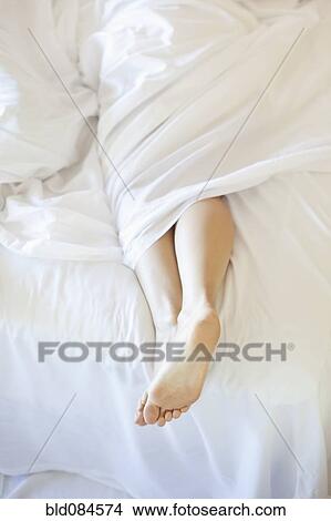 Picture - Woman's feet in bed. Fotosearch
