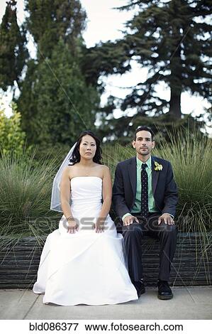 Stock Photo - Bride and groom sitting outdoors. Fotosearch