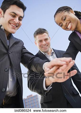 Picture - Business people clasping hands together. Fotosearch