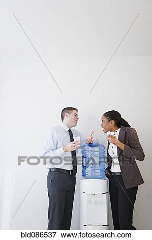 Business people talking together at water cooler View Large Photo Image Stock Photo - Business people talking together at water cooler. Fotosearch