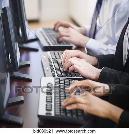 Stock Image - Business people working together in office on computers. Fotosearch
