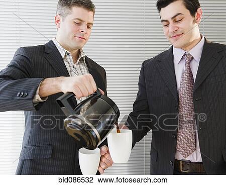 Stock Image - Businessman pouring coffee for co-worker. Fotosearch