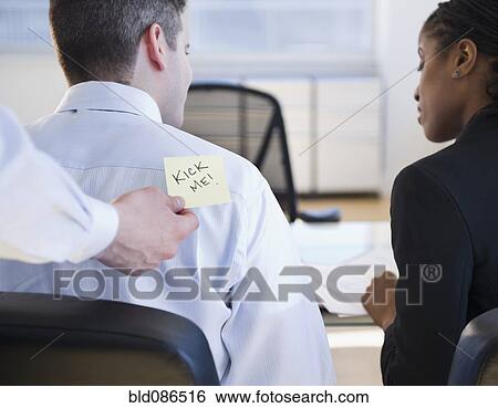 Stock Photograph - Businessman putting "kick me" sign on co-workers back. Fotosearch