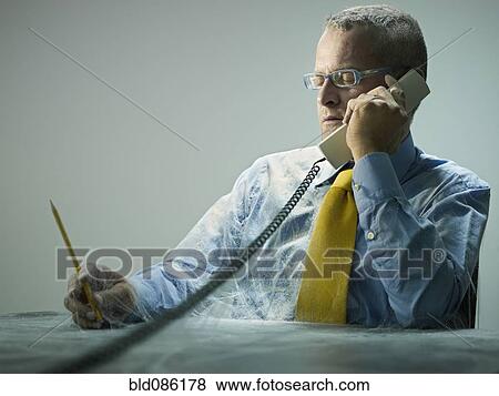 Stock Photo - Caucasian businessman covered in cobwebs talking on telephone. Fotosearch