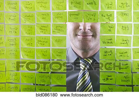 Stock Image - Caucasian businessman looking at adhesive notes on wall. Fotosearch