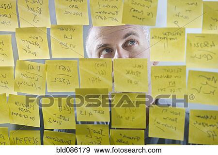 Caucasian businessman looking at adhesive notes on wall View Large Photo Image Stock Photo - Caucasian businessman looking at adhesive notes on wall. Fotosearch