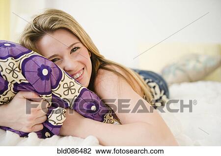 Stock Image - Caucasian teenage girl laying on bed. Fotosearch