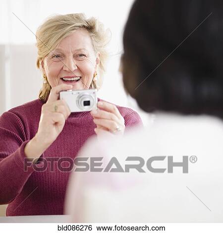Stock Photograph - Caucasian woman taking photograph of friend. Fotosearch