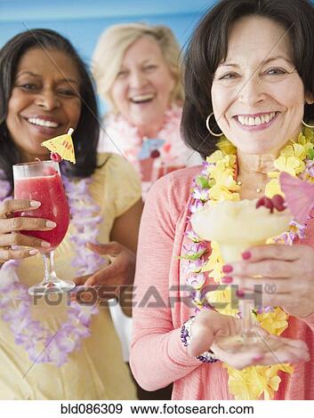 Stock Photo - Friends drinking tropical cocktails together. Fotosearch
