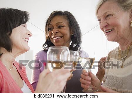Stock Image - Friends drinking white wine together. Fotosearch
