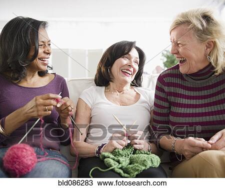 Stock Image - Friends laughing and knitting together. Fotosearch