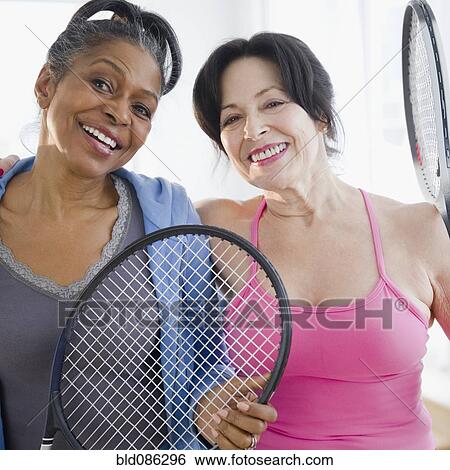 Stock Photograph - Friends standing together with tennis racquets. Fotosearch