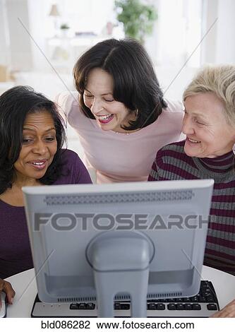 Stock Image - Friends using computer together. Fotosearch