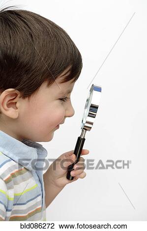 Stock Image - Hispanic boy looking through magnifying glass. Fotosearch