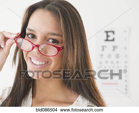 Picture - Hispanic teenage girl having eye exam. Fotosearch