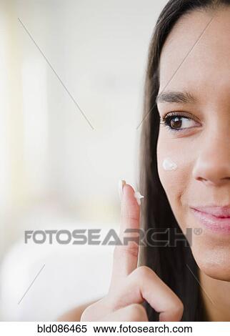 Stock Photography - Hispanic teenager applying moisturizer. Fotosearch