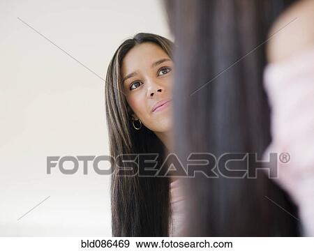 Stock Photo - Hispanic teenager looking into mirror. Fotosearch