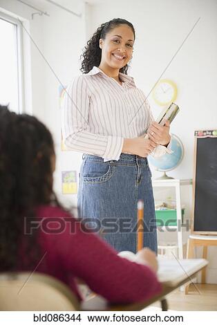 Picture - Mixed race teacher smiling in classroom. Fotosearch