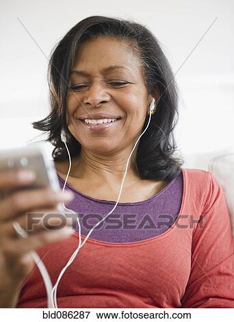 Stock Photo - Mixed race woman listening to mp3 player. Fotosearch