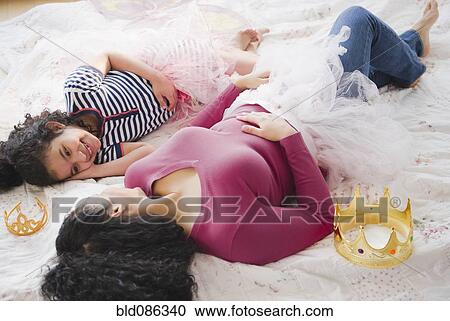 Stock Image - Mother and daughter in costumes laying on floor. Fotosearch