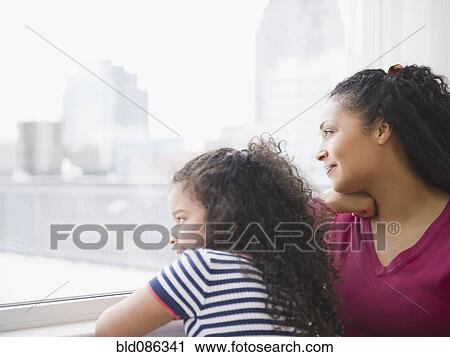 Stock Image - Mother and daughter looking out window. Fotosearch