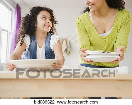 Stock Image - Mother and daughter setting the table. Fotosearch
