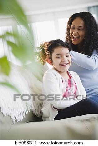 Stock Image - Mother brushing daughter's hair. Fotosearch