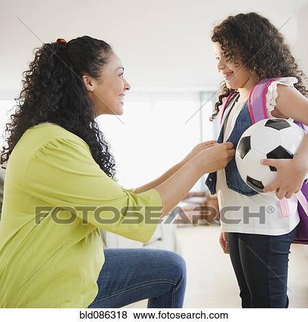 Mother dressing daughter holding soccer ball View Large Photo Image Stock Photo - Mother dressing daughter holding soccer ball. Fotosearch