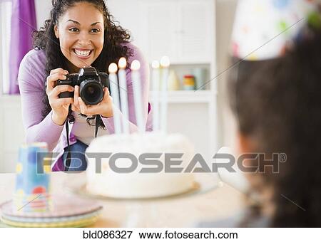 Stock Photo - Mother taking birthday picture of daughter. Fotosearch