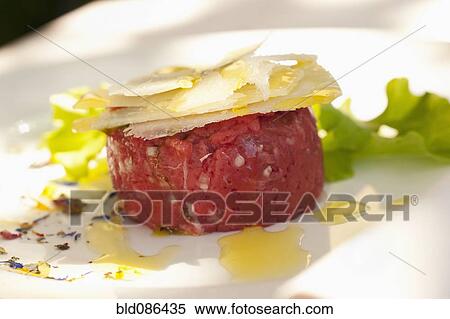 Stock Photography - Parmesan cheese atop steak tartare. Fotosearch