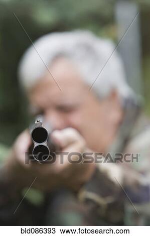 Stock Image - Senior Chilean man pointing shotgun. Fotosearch