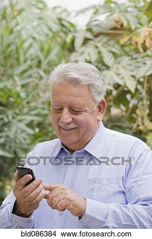 Picture - Senior Chilean man using cell phone. Fotosearch