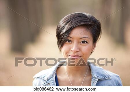 Stock Image - Smiling Asian woman outdoors. Fotosearch