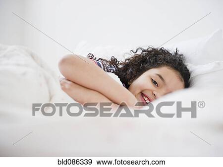 Smiling Hispanic girl laying in bed View Large Photo Image Stock Photo - Smiling Hispanic girl laying in bed. Fotosearch