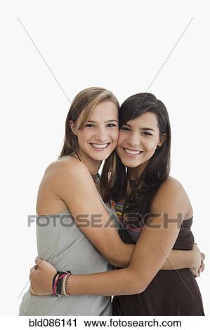 Stock Image - Smiling Hispanic sisters hugging. Fotosearch