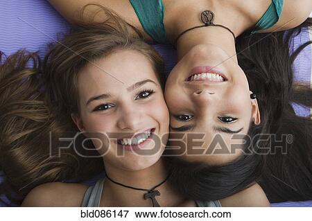 Stock Photo - Smiling Hispanic sisters laying together. Fotosearch