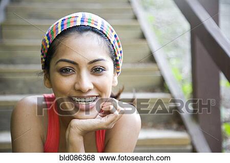 Stock Photo - Smiling Indian woman sitting on stairs. Fotosearch