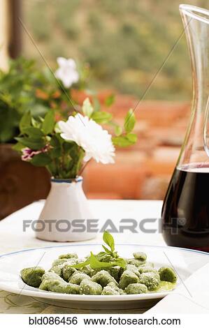 Stock Photograph - Spinach gnocchi and carafe of red wine. Fotosearch